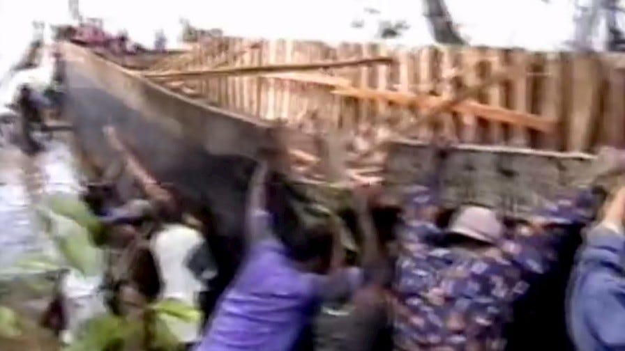 Pushing large wooden boat into river